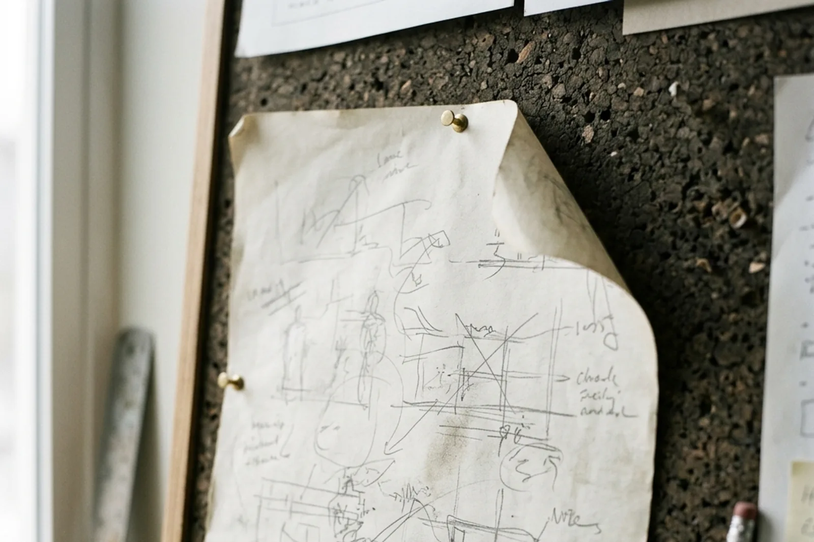 A paper draft pinned to a textured wooden board.